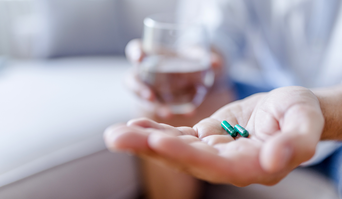 Man takes medicines with glass of water.